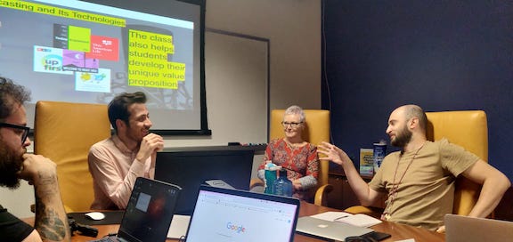 Roddy Nikpour, Marianne Barrett, and Juan Manuel Gari chat animatedly about podcasting as Bruno looks on with interest