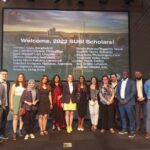 The not-late 2022 Cronkite SUSI scholar pose in front of a complete list of names