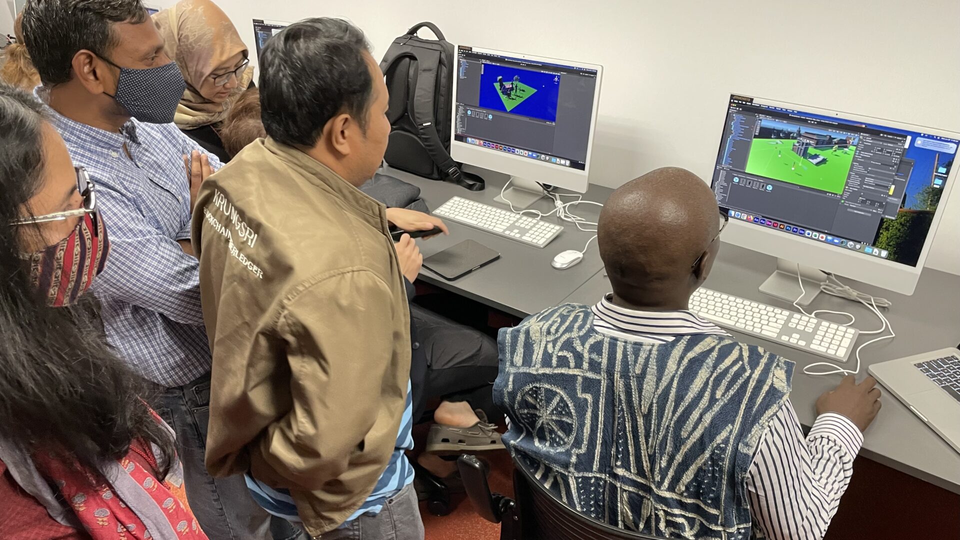 Scholars gather round to watch one of their peers manipulate images in a virtual design environment