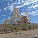 The white San Xavier del Bay Mission stands out starkly against a blue Arizona sky