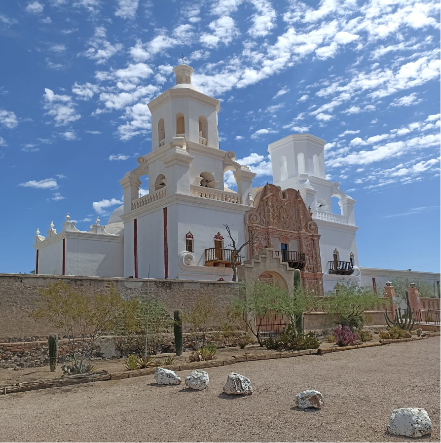 The white San Xavier del Bay Mission stands out starkly against a blue Arizona sky