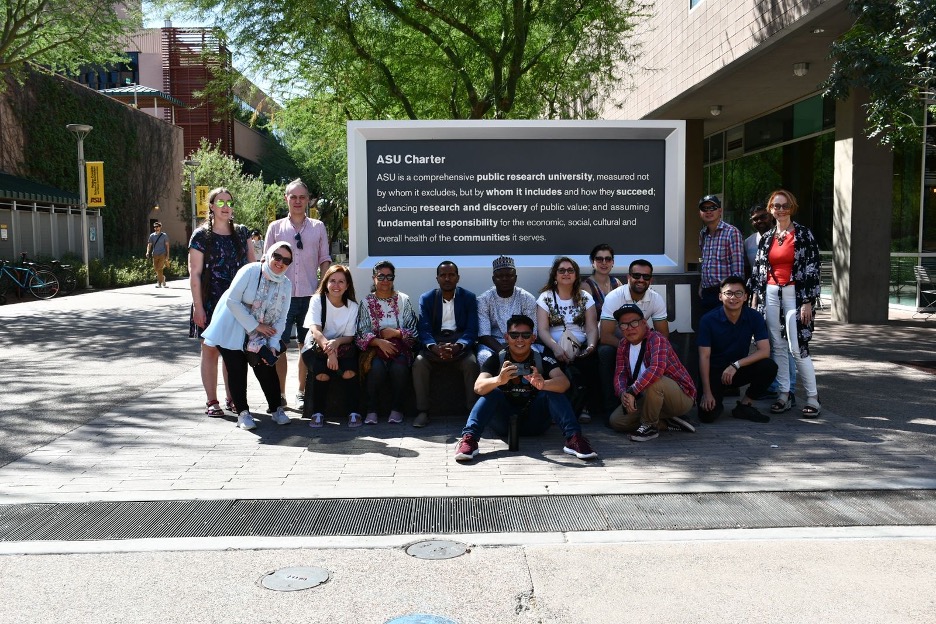 17 Media scholars, educators, and professionals pose in front of a stone tablet bearing the ASU charter on the downtown campus