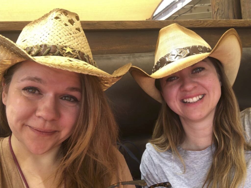 Two smiling blonde Scholars turned cowgirls with newly purchased hats