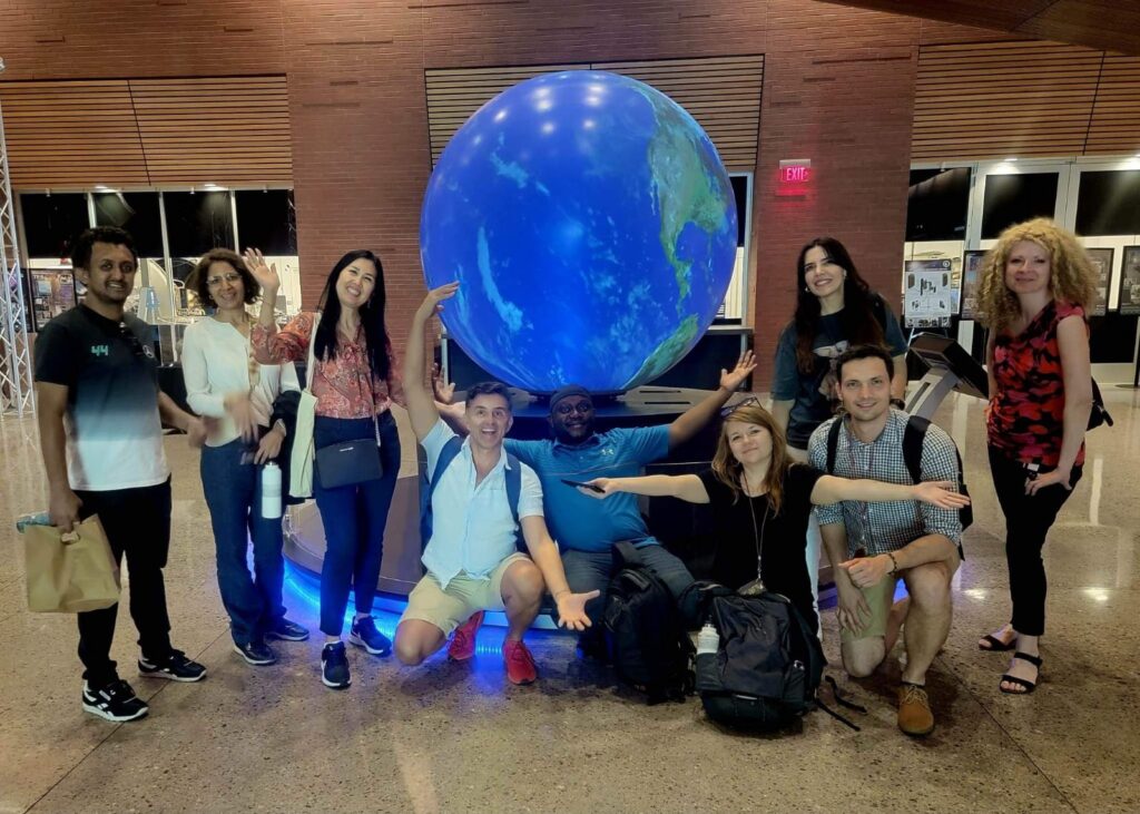 A group of scholars and a local friend pose for a group photo in front of a large model of the Earth