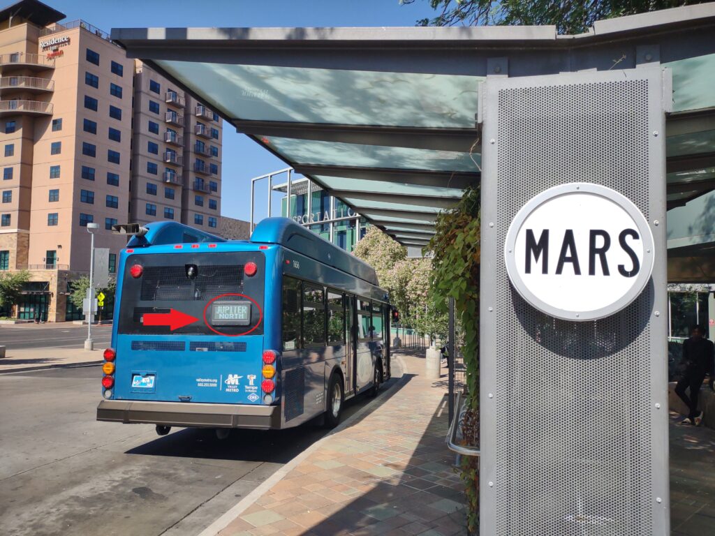 A bus stop is labeled Mars, but a nearby bus indicates it is directed toward Jupiter North