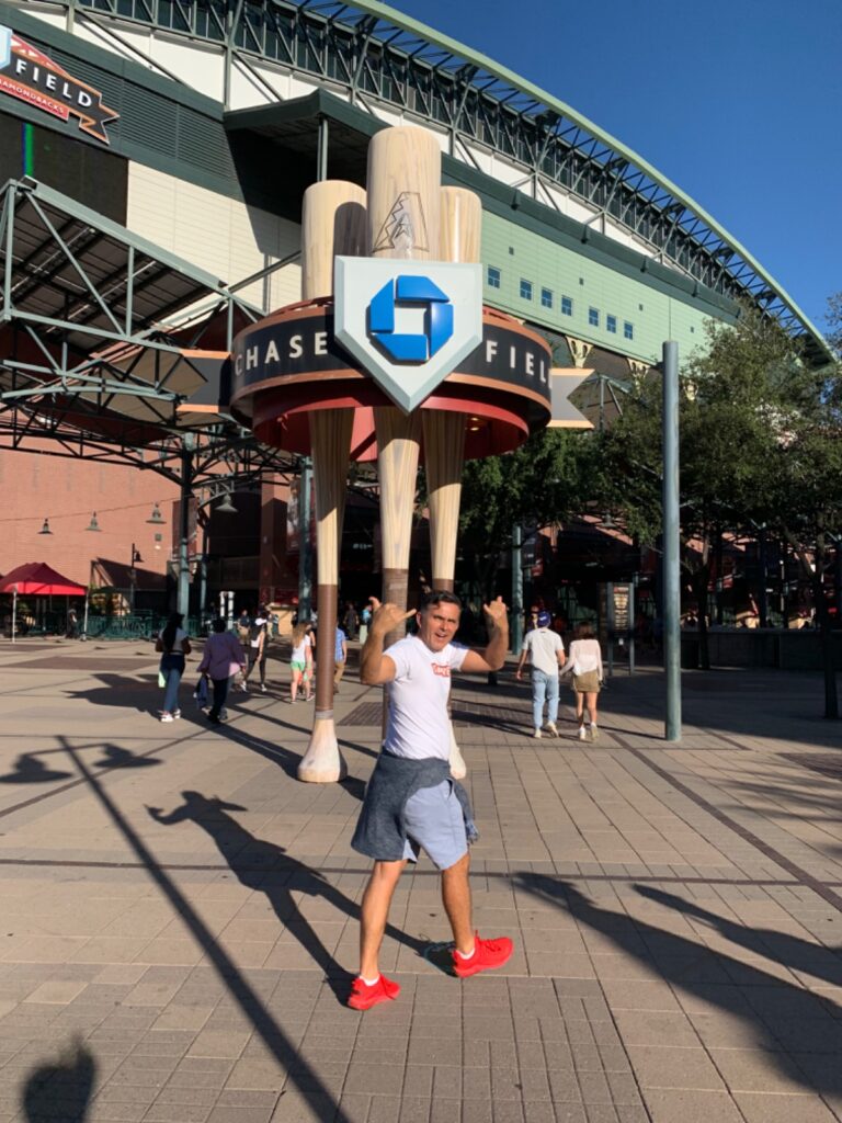 A scholar turns to salute the camera while walking towards the entrance to Chase Field