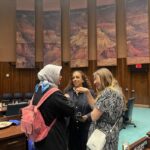 Three women scholars chatting in the Arizona State Legislature