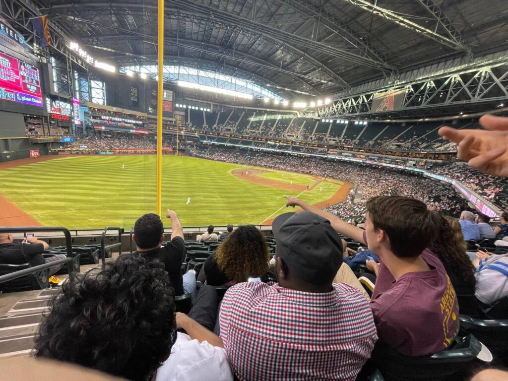 The scholars sit in the all-you-can-eat box at Chase Field in Phoenix during a Diamondbacks-Philies game