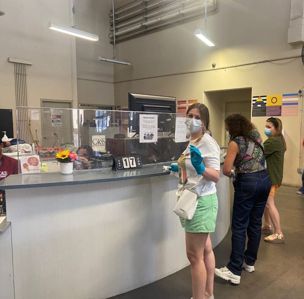 Three women wearing masks and cleaning gloves scrub surfaces in one of the communal areas of the CASS shelter in downtown Phoenix