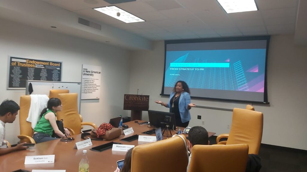 The scholars look on as a peer speaks in front of a projected slide labeled "From Strategy to PR"