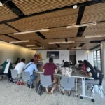 The scholars sit around a conference-style table as they debrief their experience