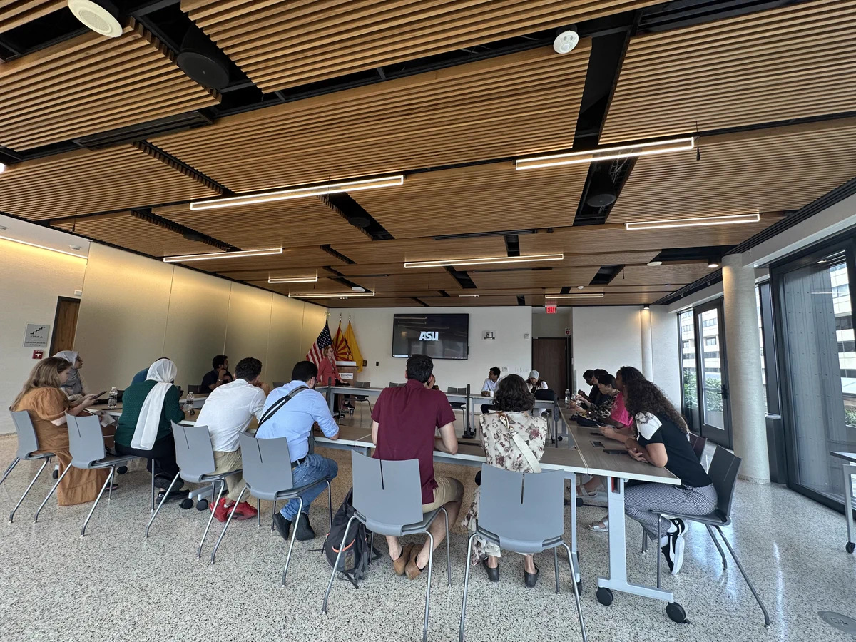 The scholars sit around a conference-style table as they debrief their experience