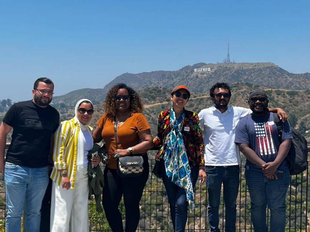 A group of scholars pose with the Hollywood sign in the background