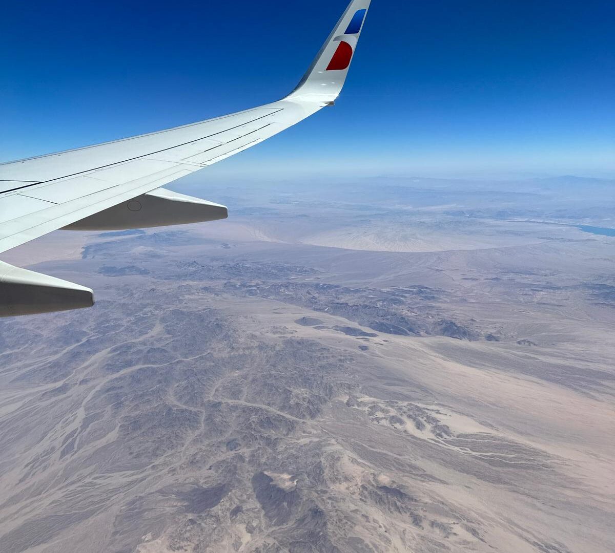 A shot of the desert from a plane window behind the wing