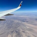 A shot of the desert from a plane window behind the wing