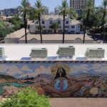 View of a small city park with a mural by Indigenous artists depicting Mother Earth in the desert