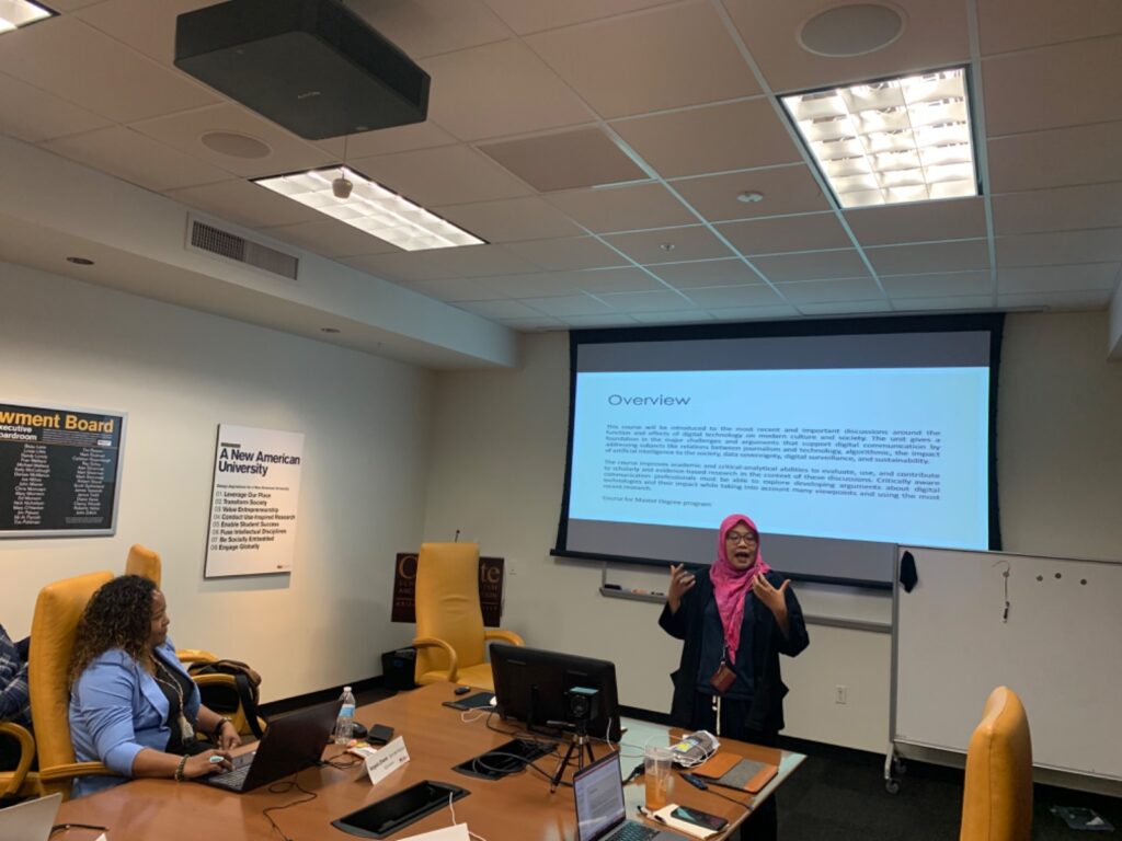 A scholar speaks animatedly in front of a slide