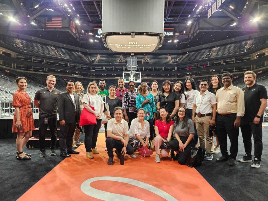 The scholars pose in front of the NBA court at the Footprint Center arena