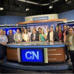 The scholars pose behind the Cronkite News anchor desk