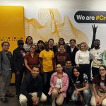 The scholars pose for a group photo in front of the 4th floor mural, under a sign reading "We are #CronkiteNation"