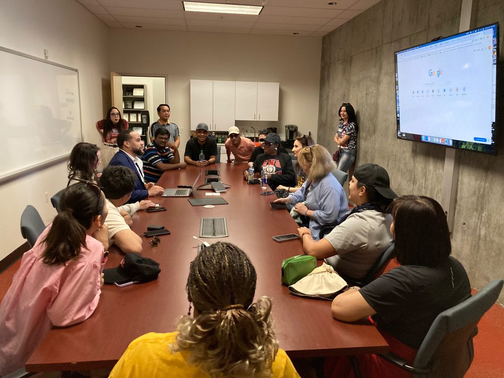 The scholars listen attentively around a conference table as they hear about the basics of baseball