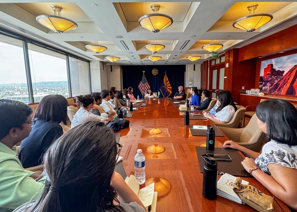 A long conference table, with large picture windows, surrounded by a flock of SUSI scholars