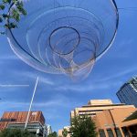 A metal sculpture appears to float against the bright blue downtown Phoenix sky