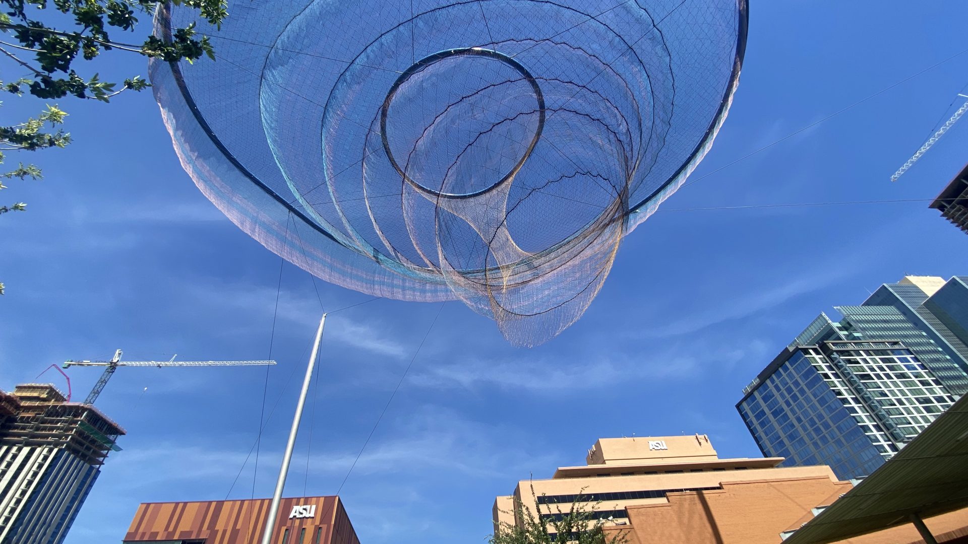 A metal sculpture appears to float against the bright blue downtown Phoenix sky